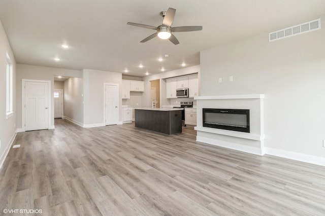 5616 Leyden Ave, Des Moines, IA 50317 - unfurnished living room featuring a ceiling fan, recessed lighting, light wood finished floors, and a glass covered fireplace