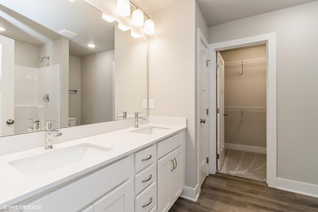 5616 Leyden Ave, Des Moines, IA 50317 - full bath featuring wood finished floors, double vanity, a shower, a walk in closet, and recessed lighting