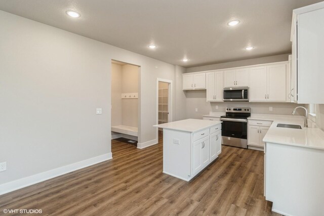 5656 Brook View Ave, Des Moines, IA 50317 - kitchen featuring stainless steel appliances, a center island, wood finished floors, white cabinetry, and recessed lighting