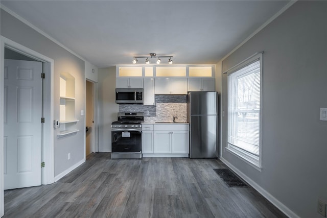 kitchen featuring white cabinetry, sink, dark hardwood / wood-style flooring, decorative backsplash, and stainless steel appliances