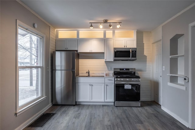 kitchen with appliances with stainless steel finishes, sink, dark wood-type flooring, and white cabinets