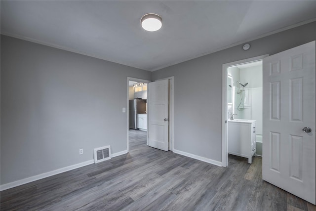 unfurnished bedroom featuring wood-type flooring and stainless steel refrigerator