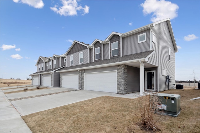 townhome / multi-family property with cooling unit, a garage, and a front lawn