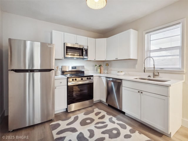 kitchen featuring white cabinetry, sink, stainless steel appliances, and light wood-type flooring