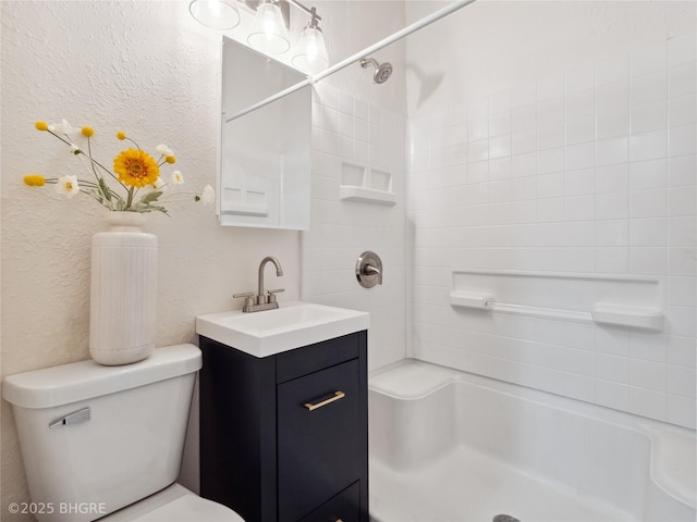 bathroom featuring vanity, tiled shower, and toilet