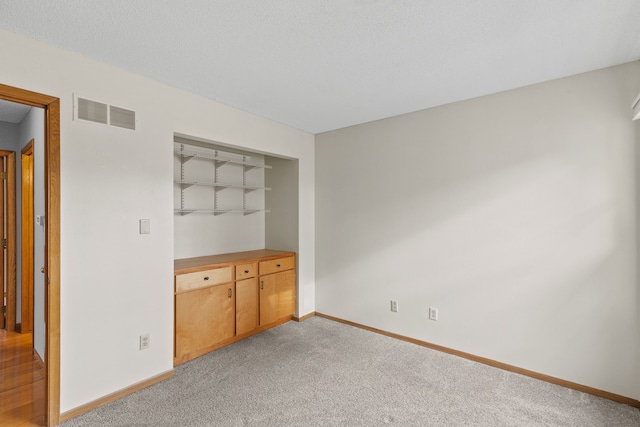 spare room with light colored carpet and a textured ceiling