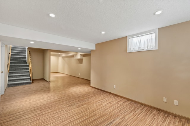 basement with light hardwood / wood-style flooring and a textured ceiling