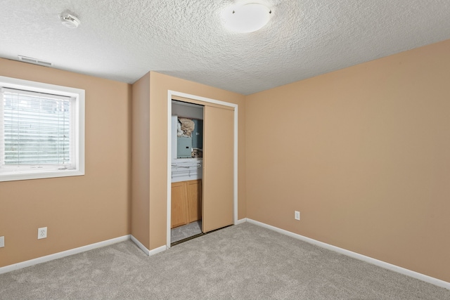 unfurnished bedroom with light carpet, a closet, and a textured ceiling