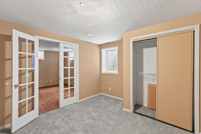 unfurnished bedroom featuring light carpet, a closet, french doors, and a textured ceiling