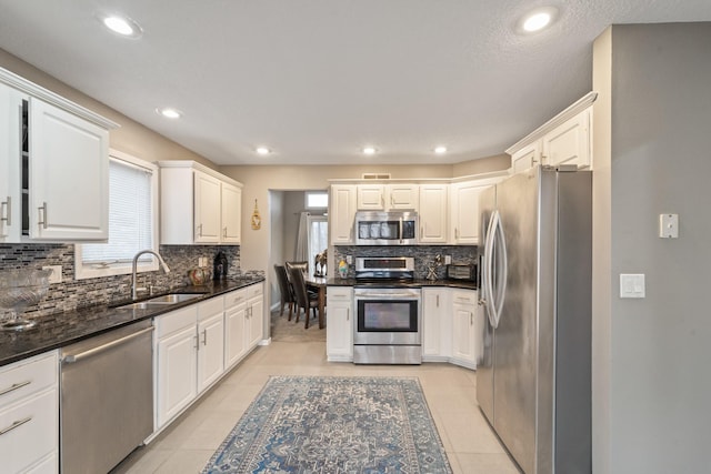 kitchen featuring white cabinetry, appliances with stainless steel finishes, sink, and light tile patterned floors