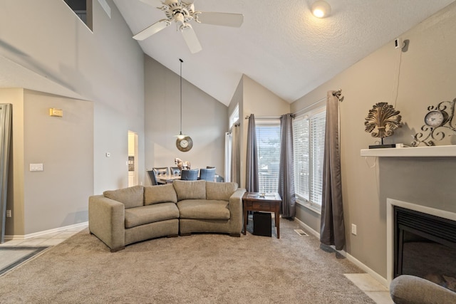 living room featuring baseboards, high vaulted ceiling, a fireplace with flush hearth, ceiling fan, and light colored carpet