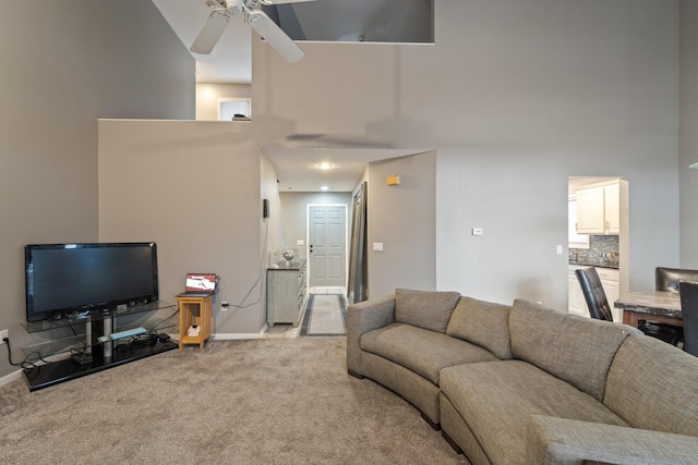 living room featuring ceiling fan, light carpet, and a high ceiling