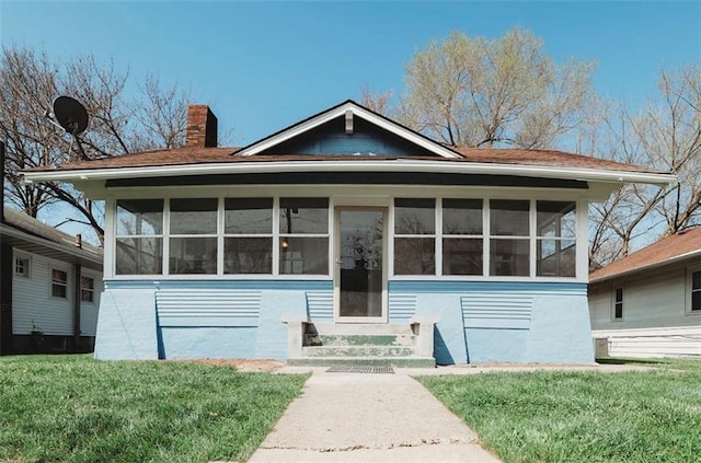 view of front of property featuring a front lawn and a sunroom