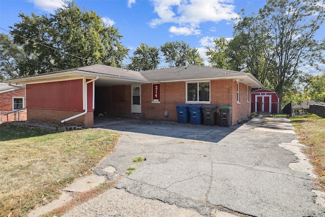 ranch-style home with a carport, a storage unit, and a front lawn