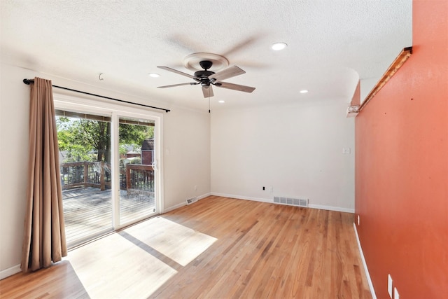 empty room with ceiling fan, light hardwood / wood-style flooring, and a textured ceiling