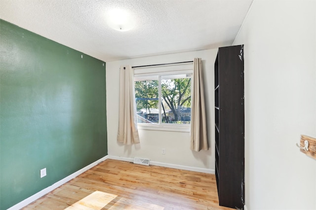 empty room with a textured ceiling and light wood-type flooring