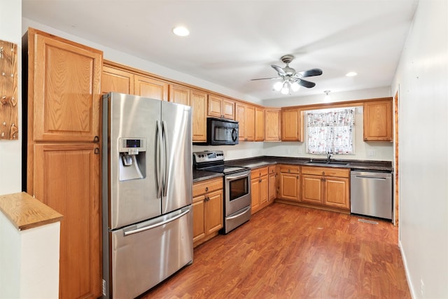 kitchen featuring dark hardwood / wood-style flooring, sink, stainless steel appliances, and ceiling fan