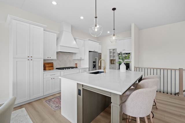 kitchen featuring high quality fridge, black gas stovetop, a breakfast bar, a sink, and custom exhaust hood