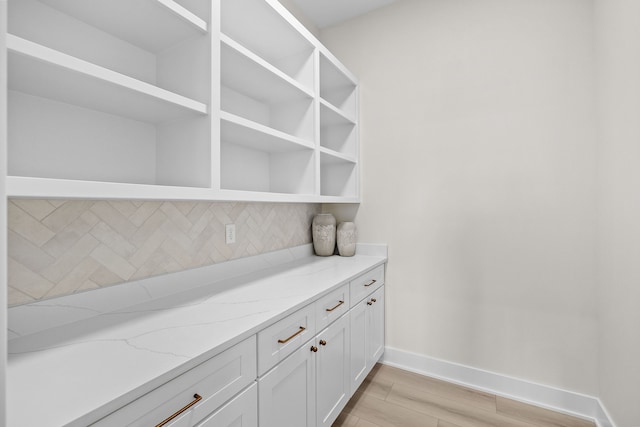 interior space featuring light wood finished floors, backsplash, and baseboards