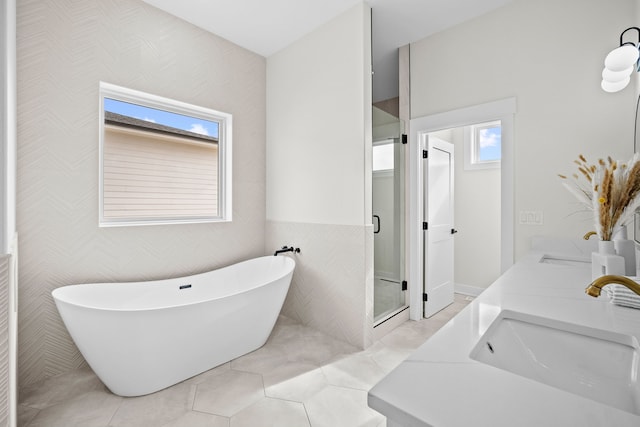 bathroom with tile walls, a freestanding bath, a sink, a shower stall, and tile patterned floors