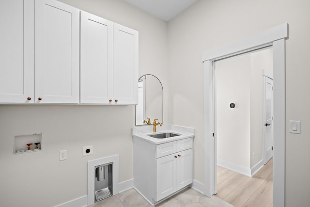 washroom with hookup for an electric dryer, washer hookup, a sink, baseboards, and cabinet space