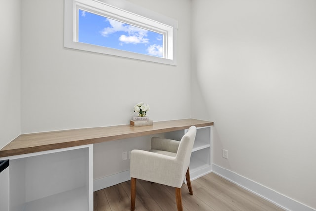 office area featuring built in desk, wood finished floors, and baseboards