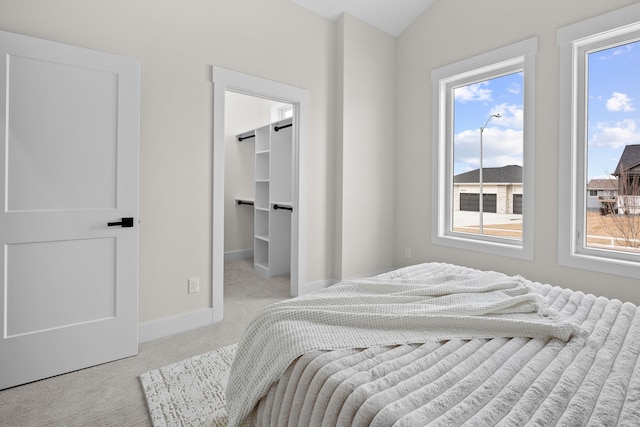 bedroom featuring a walk in closet, carpet flooring, and baseboards