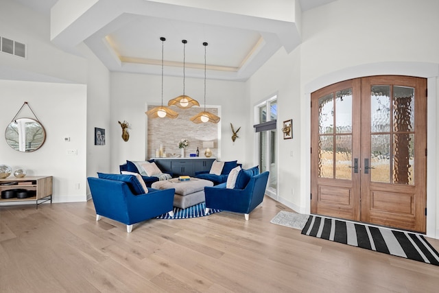 foyer with light wood finished floors, visible vents, french doors, and a tray ceiling