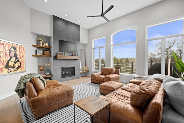 living room featuring a ceiling fan, wood finished floors, baseboards, recessed lighting, and a fireplace