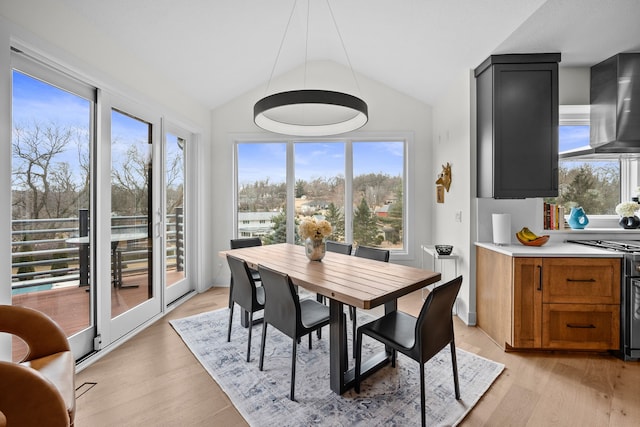 dining space with light wood-type flooring and lofted ceiling