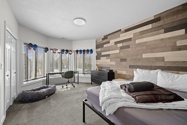 carpeted bedroom featuring wood walls and a textured ceiling