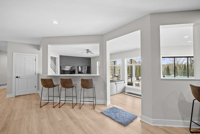 kitchen featuring light wood-type flooring, baseboards, a breakfast bar, and freestanding refrigerator