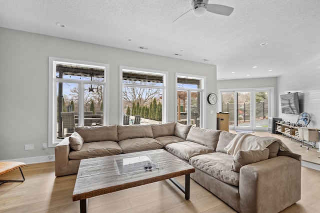 living area with light wood-type flooring, visible vents, a textured ceiling, recessed lighting, and baseboards