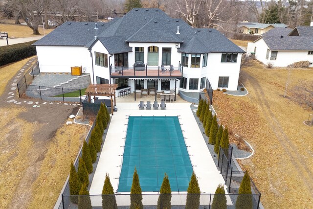 rear view of house featuring a fenced in pool, a patio, a shingled roof, and a fenced backyard