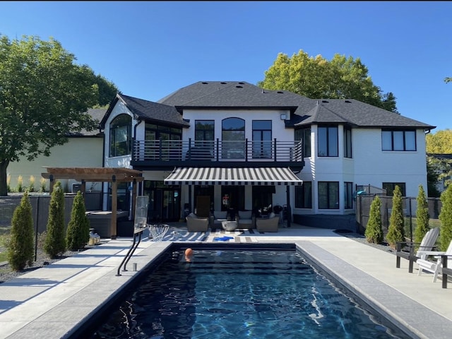 rear view of house featuring a fenced in pool, fence, an outdoor hangout area, a balcony, and a patio area