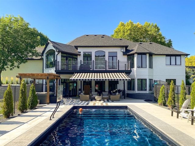 back of property featuring a pergola, a patio, fence, a fenced in pool, and a balcony