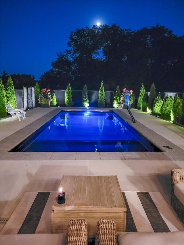 pool at twilight featuring a patio, a fenced backyard, and a fenced in pool