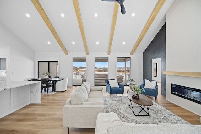 living area with a glass covered fireplace, beamed ceiling, high vaulted ceiling, and light wood-style floors