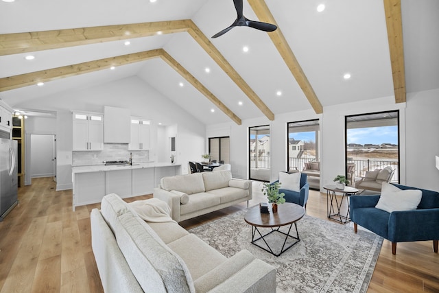 living room featuring high vaulted ceiling, beam ceiling, light wood-style flooring, recessed lighting, and ceiling fan