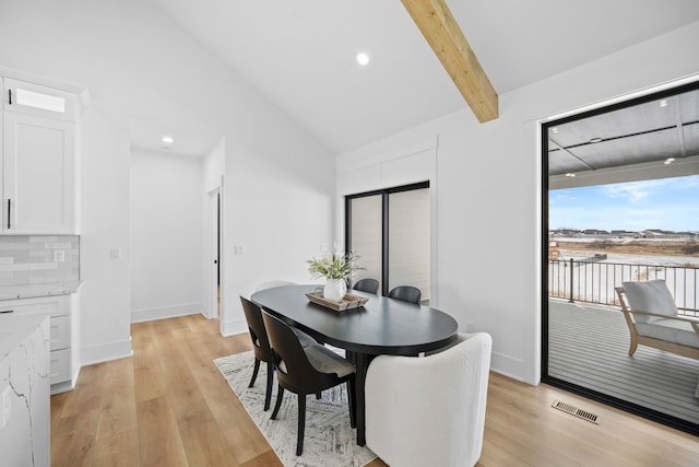 dining room featuring lofted ceiling with beams, light wood-style floors, visible vents, and baseboards