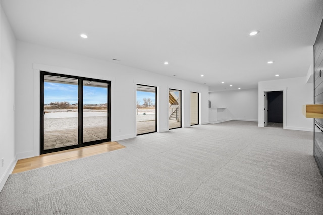 unfurnished living room featuring recessed lighting, baseboards, and light colored carpet