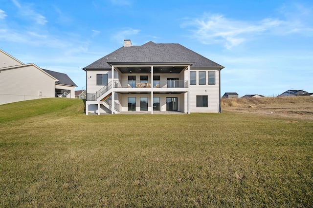 rear view of property featuring a patio area, a lawn, a chimney, and roof with shingles