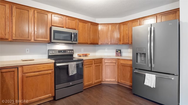 kitchen featuring dark wood-type flooring, a textured ceiling, and appliances with stainless steel finishes