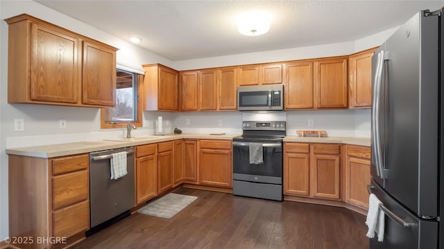 kitchen featuring appliances with stainless steel finishes, dark hardwood / wood-style flooring, sink, and a textured ceiling