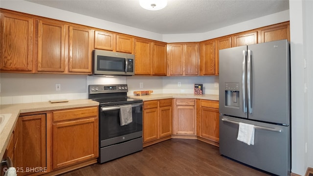 kitchen with dark hardwood / wood-style flooring, a textured ceiling, and appliances with stainless steel finishes