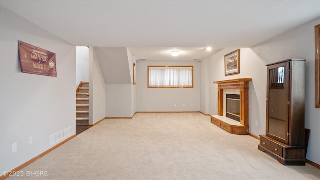 unfurnished living room with a tiled fireplace and light colored carpet