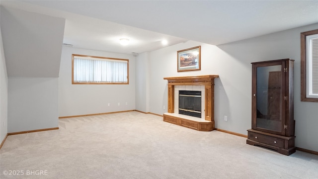 unfurnished living room featuring a tiled fireplace and light colored carpet