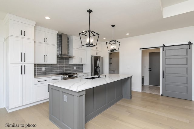 kitchen featuring white cabinetry, a large island with sink, and wall chimney exhaust hood