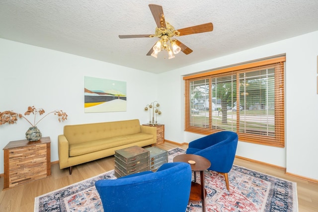 living room with hardwood / wood-style flooring, ceiling fan, and a textured ceiling