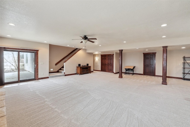 interior space with decorative columns, ceiling fan, light carpet, and a textured ceiling